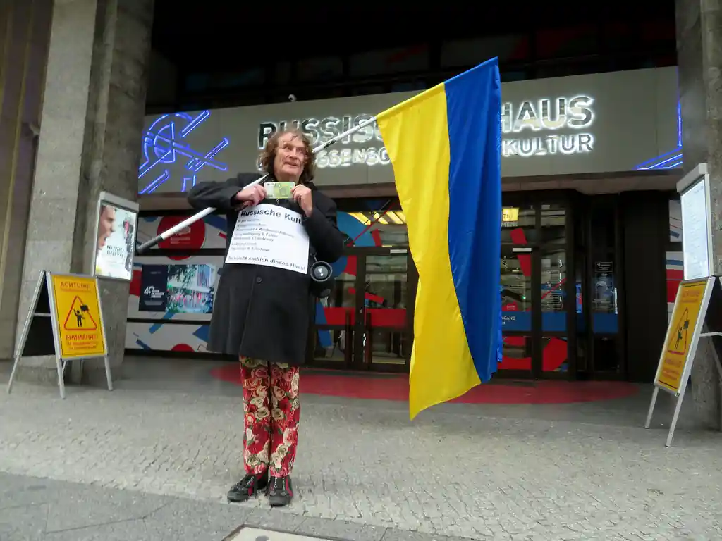 Henry Lindemeier protestiert vor dem Russischen Haus in Berlin mit einer großen ukrainischen Flagge.