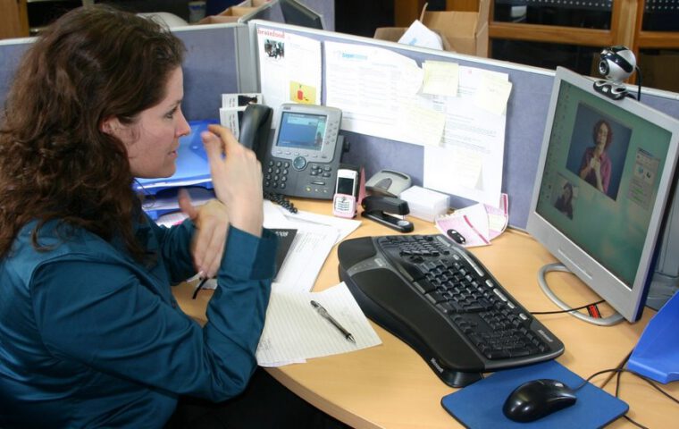 Eine gehörlose oder schwerhörige Person nutzt am Arbeitsplatz einen Video-Relay-Dienst mit Gebärdensprachdolmetschung.