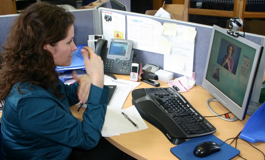 Eine gehörlose oder schwerhörige Person nutzt am Arbeitsplatz einen Video-Relay-Dienst mit Gebärdensprachdolmetschung.