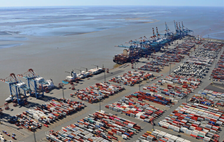 Containerhafen in Bremerhaven mit Containerbrücken, Schiffen und gestapelten Containern.
