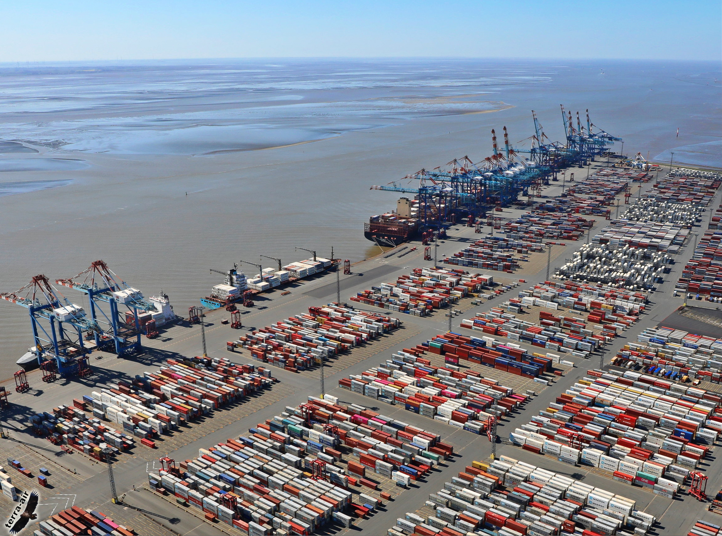 Containerhafen in Bremerhaven mit Containerbrücken, Schiffen und gestapelten Containern.