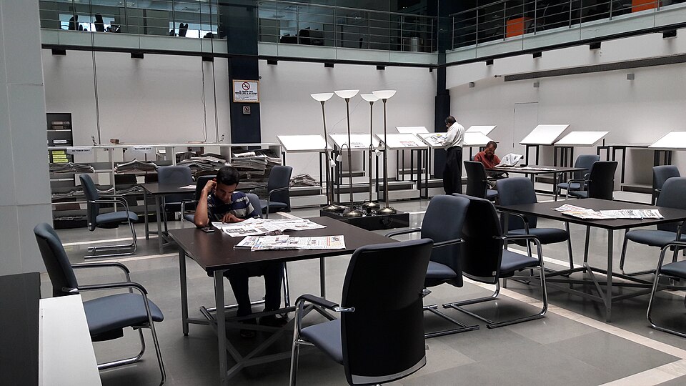 Zeitungsbereich einer Bibliothek mit Leserinnen und Lesern.